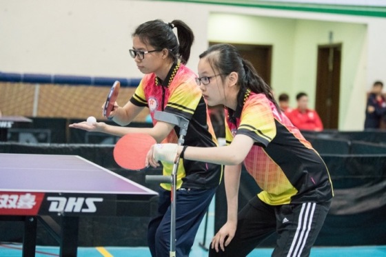 焦瑾珊同學（左）於女子乒乓球團體賽與隊友一同撃敗對手，摘下桂冠。 