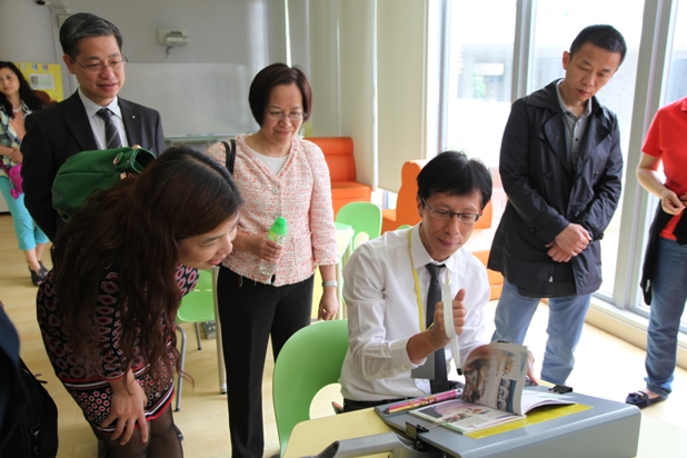 Mr. fong cheung fat (first left), chief executive officer of the association, and mrs. louisa law (left-second), deputy chief executive officer of the association, accompanied the guests to see the demonstration of the page-turning aid used in the school.