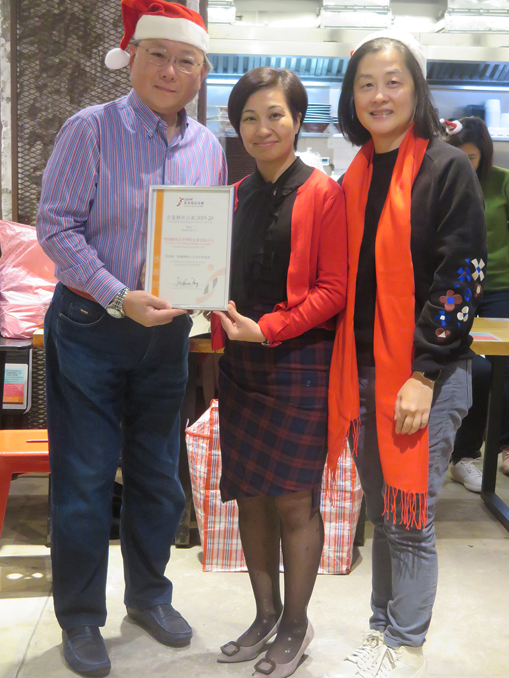 Mr. Andrew W. K. Luk (left), Chairperson of the St. Paul's Co-educational College Alumni Association received certificate from Ms Winnie W. C. Leung (right), Council member of the Association and Mrs. Dawn S. F. Liu (centre), Head of Service (Children and Family Support Service).