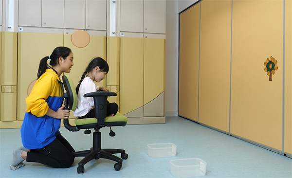 Ms. Leung uses a computer chair to train children's abilities of hand-eye coordination and postural control.